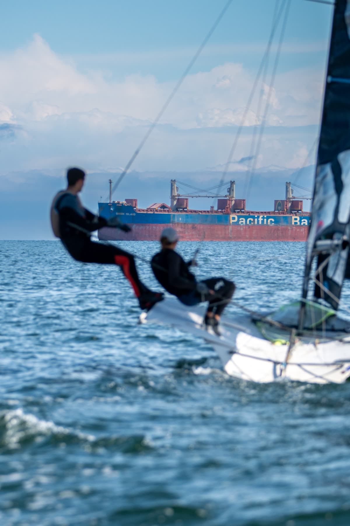 Zawodniczki na trapezie 49er FX, w tle statek towarowy na redzie